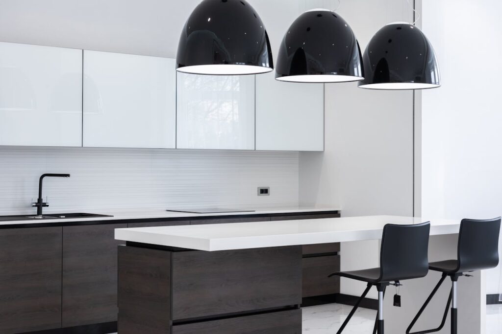 Interior of modern kitchen with minimalist furniture and creative lamps hanging above counter and bar chairs