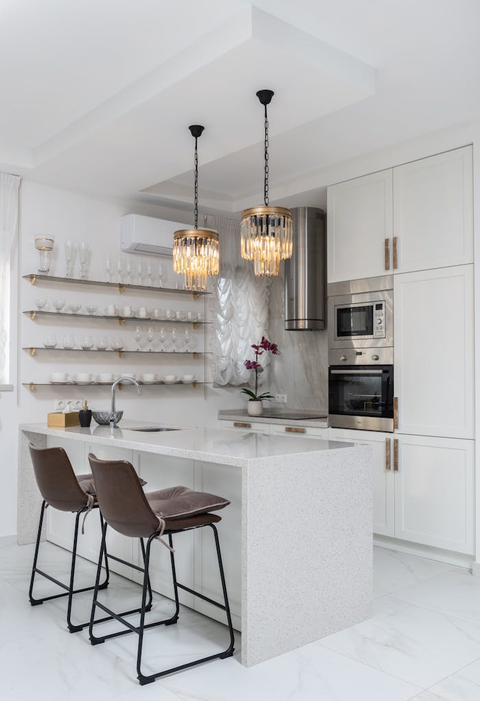 Sleek modern kitchen interior with white cabinets and elegant pendant lights.